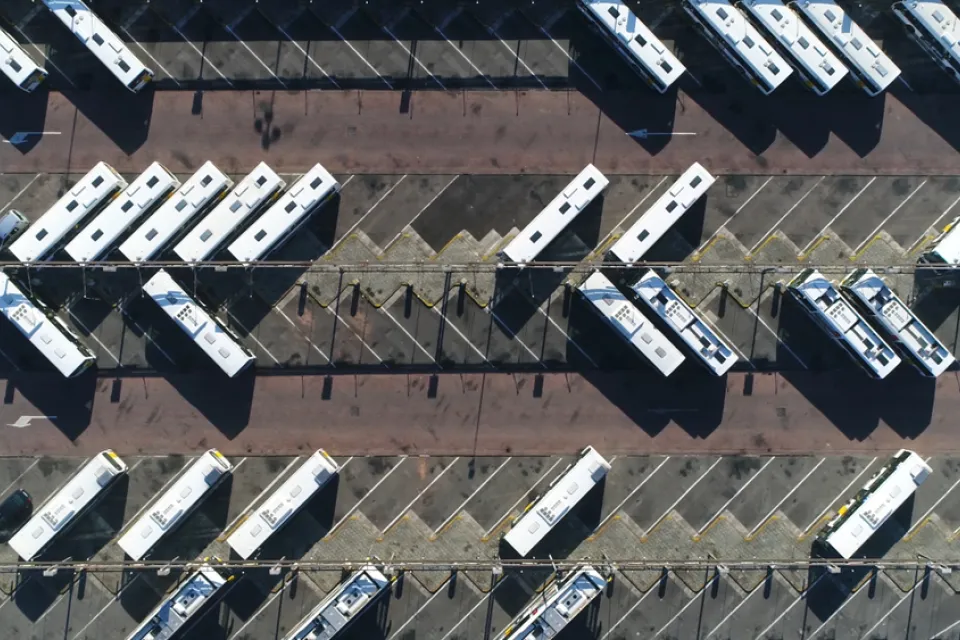 Aerial view from directly overhead of buses parked in large asphalt lot